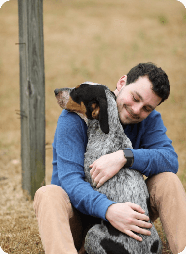 A team member at Doggies Gone Wild in Miami Gardens embracing a dog, demonstrating the loving and attentive care we offer to every pet in our facility.